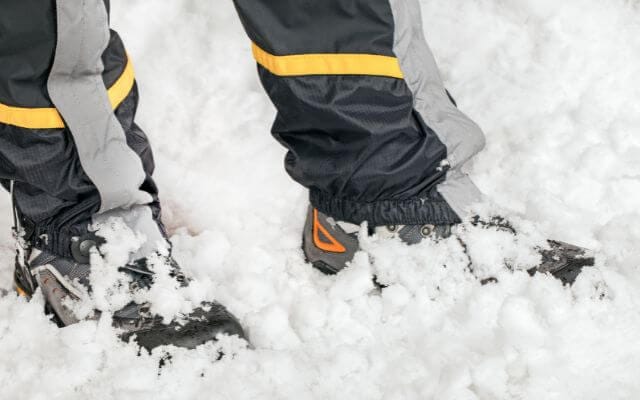 Close-up of a hiker's boots and pants, featuring the best winter hiking gear for walking through deep snow